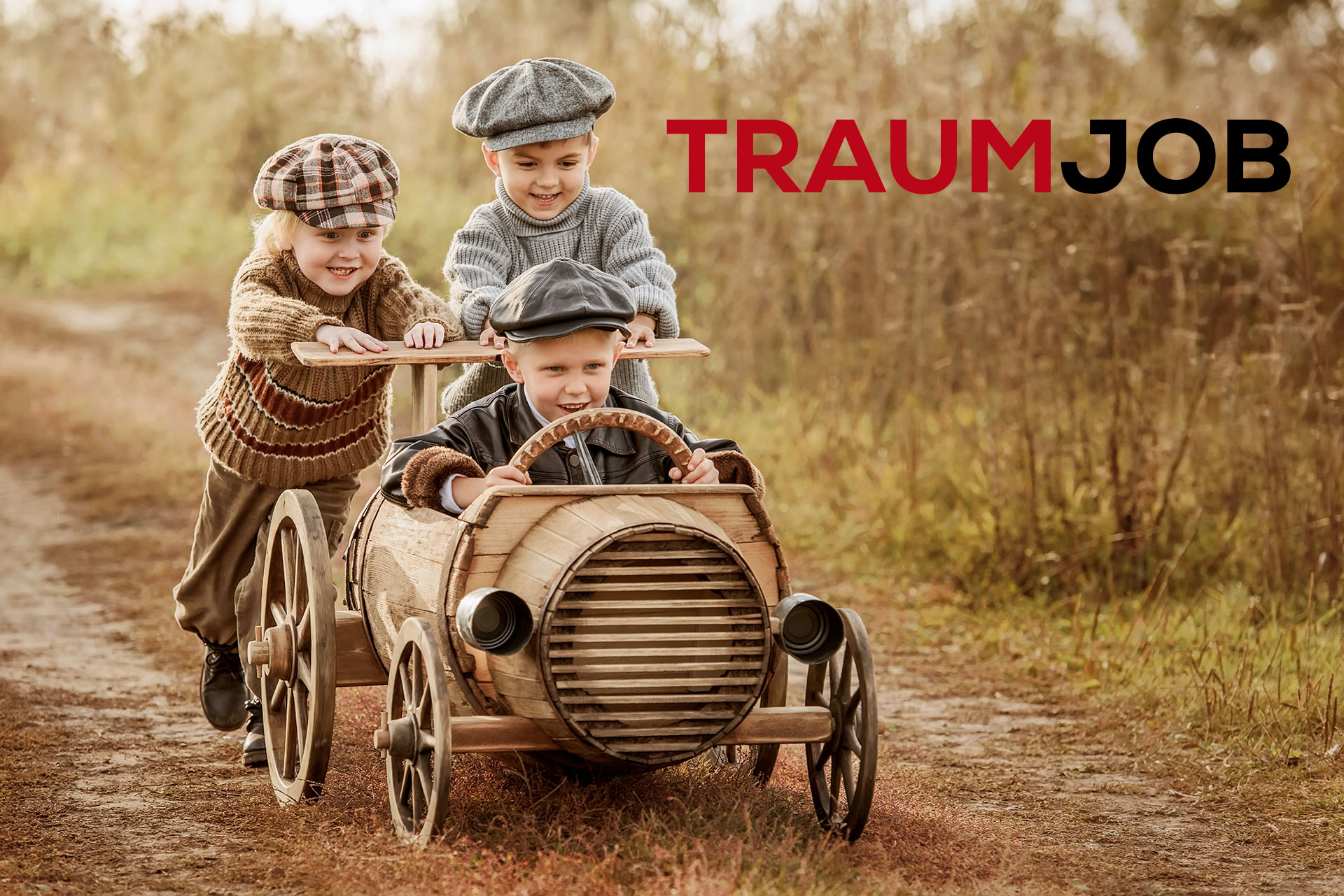 Drei kleine Kinder in Vintage-Kleidung spielen lächelnd und vergnügt auf einem Feldweg mit einem hölzernen Spielzeugauto. Rechts im Bild steht in großen Buchstaben das Wort TRAUMJOB.